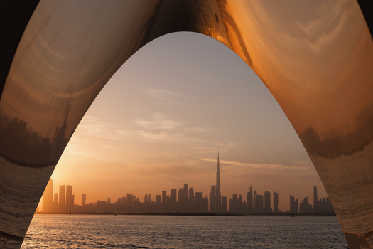 View of the iconic Burj Khalifa and the Dubai skyline silhouetted against a golden sunset sky framed by a modern archway Dubai United Arab Emirates.