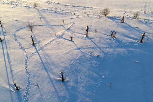 Aerial view of the Hill of Angels featuring wooden sculptures and crosses scattered across a snow covered field with long shadows in Traku rajonas Vilniaus apskritis Lithuania. Aerial view of the Hill of Angels featuring wooden sculptures and crosses scattered across a snow covered field with long shadows in Traku rajonas Vilniaus apskritis Lithuania.