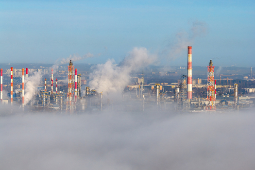 Aerial view of big refinery complex with tall chimneys releasing white smoke piercing through a sea of fog Gdansk Pomorskie voivodeship Poland. Aerial view of big refinery complex with tall chimneys releasing white smoke piercing through a sea of fog Gdansk Pomorskie voivodeship Poland.