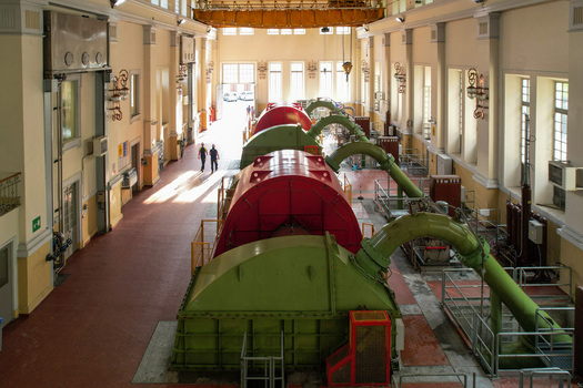 Aerial view of the interior of the Centrale idroelettrica di Villa featuring large turbines industrial windows and workers walking in the hall in Ceresole Reale Piedmont Italy. Aerial view of the interior of the Centrale idroelettrica di Villa featuring large turbines industrial windows and workers walking in the hall in Ceresole Reale Piedmont Italy.