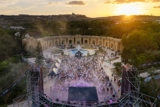 Attard Malta 20 September 2026 Aerial view of a music festival at Park Nazzjonali Ta Qali with a large crowd stage central fountain and stone walls under a golden sunset. Attard Malta 20 September 2026 Aerial view of a music festival at Park Nazzjonali Ta Qali with a large crowd stage central fountain and stone walls under a golden sunset.