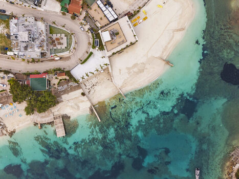 Aerial view of the coastal town of Ksamil featuring turquoise waters sandy beaches wooden piers and nearby buildings in Ksamil Vlore County Albania. Aerial view of the coastal town of Ksamil featuring turquoise waters sandy beaches wooden piers and nearby buildings in Ksamil Vlore County Albania.