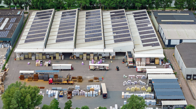 Aerial view of Boekelermeer industrial facility with a large warehouse rooftop solar panels loading docks parked trucks and outdoor storage in Alkmaar Noord Holland Netherlands.