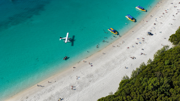 Aerial view of Whitehaven Beach with turquoise water white sand a seaplane small boats and people on the beach in Whitsundays Queensland Australia.