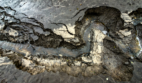 Aerial view of a muddy eroded landscape with a small stream cutting through dark cracked soil in Latvia. Aerial view of a muddy eroded landscape with a small stream cutting through dark cracked soil in Latvia.