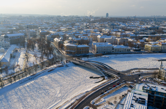 Aerial view of the snow covered cityscape of Vilnius featuring the Mindaugas Bridge over the frozen Neris River and historic architecture Vilnius County Lithuania.