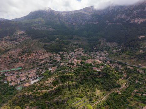 Aerial view of the historic village of Valldemossa nestled in the lush green Tramuntana mountains with stone houses and terraced slopes Valldemossa Balearic Islands Spain.