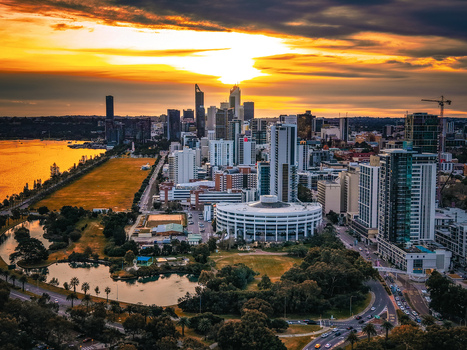 Aerial view of the Perth skyline at sunset with skyscrapers reflecting in the Swan River lush parkland and urban roads in Perth Western Australia Australia.