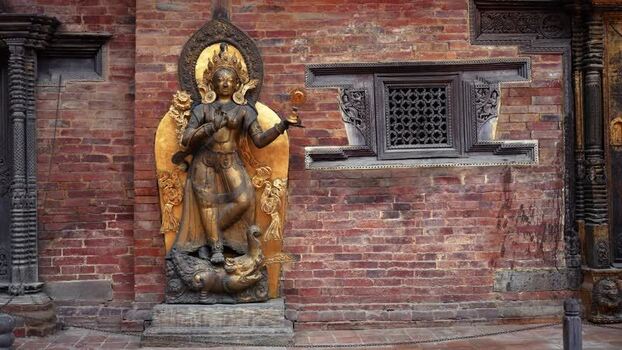 View of a golden deity statue against a brick wall Nepal.