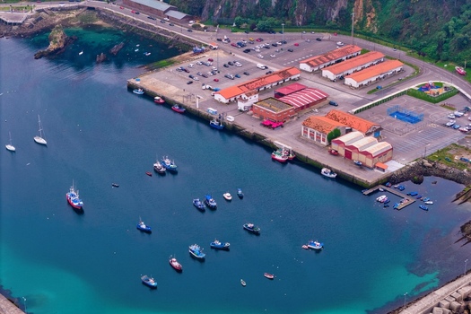Aerial view of the harbor of Cudillero with fishing boats moored in turquoise water and buildings with orange roofs along the waterfront in Cudillero Asturias Spain. Aerial view of the harbor of Cudillero with fishing boats moored in turquoise water and buildings with orange roofs along the waterfront in Cudillero Asturias Spain.