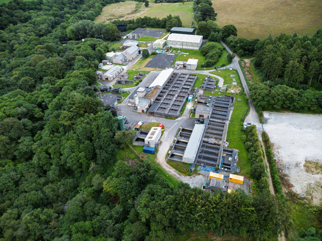 Aerial view of the Restormel water treatment facility featuring rectangular filtration tanks and industrial buildings surrounded by dense woodland and green fields in Restormel England United Kingdom. Aerial view of the Restormel water treatment facility featuring rectangular filtration tanks and industrial buildings surrounded by dense woodland and green fields in Restormel England United Kingdom.