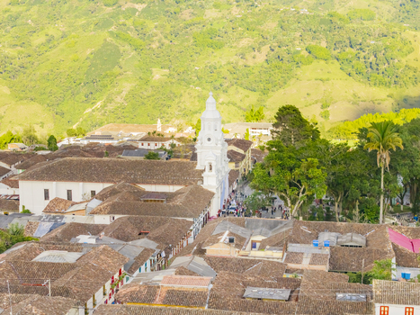 Aerial view of white tower piercing the skyline amidst terracotta roofs framed by verdant mountains Salamina Caldas Colombia. Aerial view of white tower piercing the skyline amidst terracotta roofs framed by verdant mountains Salamina Caldas Colombia.