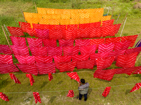Narayanganj Bangladesh 30 March 2026 Aerial view of vibrant textiles displayed on bamboo frames creating a striking contrast against the lush green field.