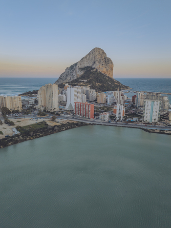 Aerial view of the Penon de Ifach rock formation rising above the coastal town of Calp with high rise buildings and the salt lake in the foreground Calp Valencian Community Spain. Aerial view of the Penon de Ifach rock formation rising above the coastal town of Calp with high rise buildings and the salt lake in the foreground Calp Valencian Community Spain.