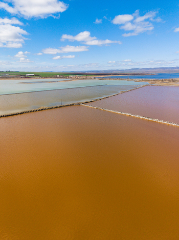 Aerial view of Lake Atanasovsko salt pans with vibrant orange and green water separated by wooden barriers under a blue sky Burgas Burgas Bulgaria. Aerial view of Lake Atanasovsko salt pans with vibrant orange and green water separated by wooden barriers under a blue sky Burgas Burgas Bulgaria.