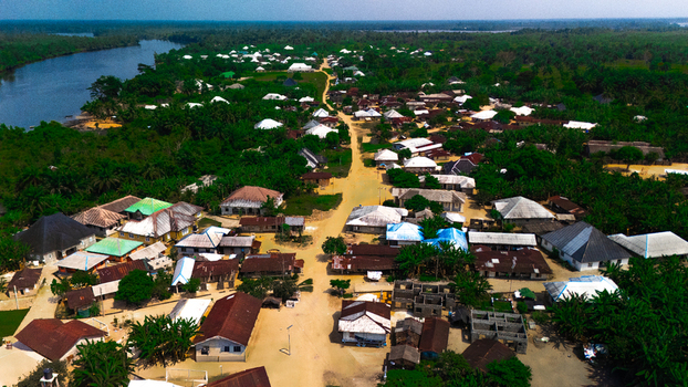 Aerial view of the village of Abua featuring numerous houses with metal roofs dirt roads and surrounding lush tropical vegetation in Abua Rivers Nigeria. Aerial view of the village of Abua featuring numerous houses with metal roofs dirt roads and surrounding lush tropical vegetation in Abua Rivers Nigeria.