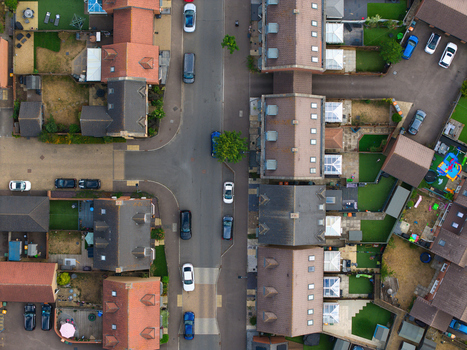 Aerial view of a modern residential housing estate with terraced houses private gardens and parked cars on the street in Bedford England United Kingdom. Aerial view of a modern residential housing estate with terraced houses private gardens and parked cars on the street in Bedford England United Kingdom.