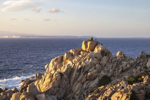 View of the granite rock formations of Capo Testa with people standing on the summit overlooking the Mediterranean Sea at sunset Capo Testa Sardegna Italy.