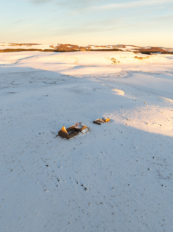 Aerial view of sun kissed snow blanketing the ruins and landscape with hints of golden light reflecting off the pristine surface Nasbinals Occitanie France.