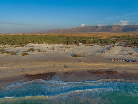 Aerial view of the golden sands meeting turquoise waters fringed by verdant trees and distant mountains Kadrihnitin Socotra Yemen. Aerial view of the golden sands meeting turquoise waters fringed by verdant trees and distant mountains Kadrihnitin Socotra Yemen.