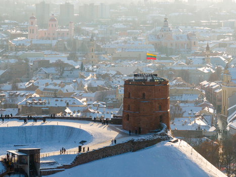 Aerial view of Gediminas Tower on a snow covered hill overlooking the historic rooftops and church domes of the city in Vilnius County Lithuania.
