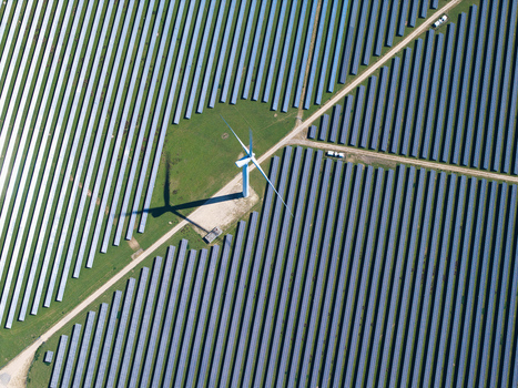 Aerial view of Chelveston Wind Farm with a single wind turbine surrounded by vast rows of solar panels on a sunny day in Wellingborough England United Kingdom. Aerial view of Chelveston Wind Farm with a single wind turbine surrounded by vast rows of solar panels on a sunny day in Wellingborough England United Kingdom.