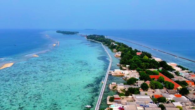 Aerial view of Pulau Tidung Besar featuring a long bridge connecting the islands surrounded by turquoise waters coral reefs and lush greenery in South Kepulauan Seribu Jakarta Indonesia.