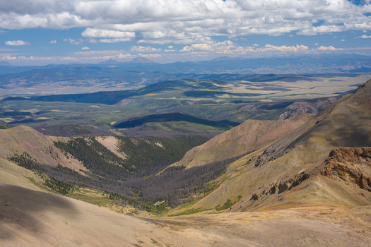 View of San Luis Peak and the surrounding rugged mountain landscape with deep valleys evergreen forests and dramatic cloud shadows in Creede Colorado United States. View of San Luis Peak and the surrounding rugged mountain landscape with deep valleys evergreen forests and dramatic cloud shadows in Creede Colorado United States.