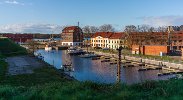 View of the historic harbor and marina in Klaipeda with traditional brick buildings moored boats and calm water under a clear blue sky in Klaipeda Klaipeda County Lithuania. View of the historic harbor and marina in Klaipeda with traditional brick buildings moored boats and calm water under a clear blue sky in Klaipeda Klaipeda County Lithuania.