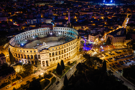 Aerial view of the illuminated Pula Arena at night surrounded by the historic city streets and urban lights in Pula Istria County Croatia. Aerial view of the illuminated Pula Arena at night surrounded by the historic city streets and urban lights in Pula Istria County Croatia.