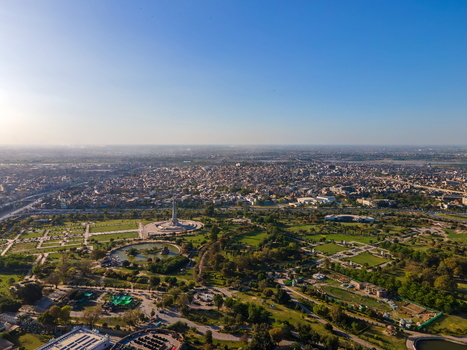 Aerial view of Minar e Pakistan monument surrounded by lush green gardens pathways and the sprawling urban cityscape of Lahore Punjab Pakistan.