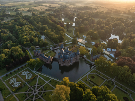 Aerial view of De Haar Castle with its medieval towers and moat surrounded by manicured formal gardens and dense green forests under a warm sunset light Utrecht Utrecht Netherlands. Aerial view of De Haar Castle with its medieval towers and moat surrounded by manicured formal gardens and dense green forests under a warm sunset light Utrecht Utrecht Netherlands.