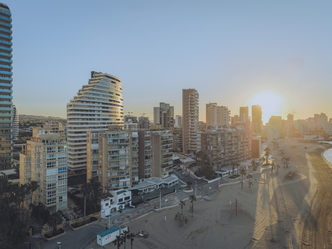 Aerial view of the coastal skyline of Calp at sunset featuring modern high rise apartment buildings a sandy beach and long shadows on the promenade in Calp Valencian Community Spain. Aerial view of the coastal skyline of Calp at sunset featuring modern high rise apartment buildings a sandy beach and long shadows on the promenade in Calp Valencian Community Spain.