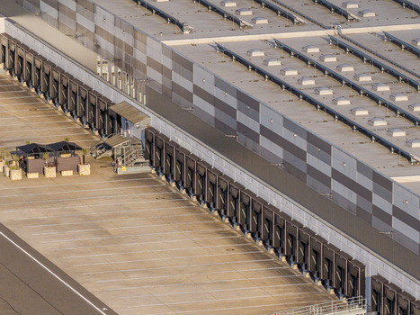 Aerial view of a large warehouse facility with multiple loading docks a concrete parking area and a modern roof structure in Grunheide Mark Brandenburg Germany. Aerial view of a large warehouse facility with multiple loading docks a concrete parking area and a modern roof structure in Grunheide Mark Brandenburg Germany.