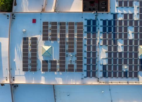 Aerial view of a commercial rooftop covered in rows of solar panels with a skylight and ventilation units in Las Vegas Nevada United States. Aerial view of a commercial rooftop covered in rows of solar panels with a skylight and ventilation units in Las Vegas Nevada United States.