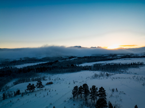Aerial view of the Arctic landscape at sunset with low hanging fog over snow covered terrain and pine trees in Tromso Troms Norway. Aerial view of the Arctic landscape at sunset with low hanging fog over snow covered terrain and pine trees in Tromso Troms Norway.