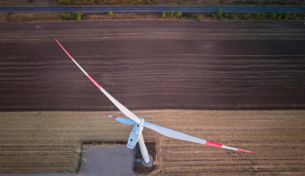 Aerial view of a wind turbine standing in a vast agricultural field with contrasting soil patterns and a road in the background in Vladimirovac Vojvodina Serbia. Aerial view of a wind turbine standing in a vast agricultural field with contrasting soil patterns and a road in the background in Vladimirovac Vojvodina Serbia.