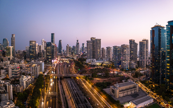 Aerial view of the modern skyline of Tel Aviv Yafo at dusk featuring illuminated skyscrapers busy highways and railway tracks in the city center Tel Aviv Yafo Tel Aviv District Israel. Aerial view of the modern skyline of Tel Aviv Yafo at dusk featuring illuminated skyscrapers busy highways and railway tracks in the city center Tel Aviv Yafo Tel Aviv District Israel.