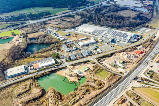 Aerial view of industrial warehouses and commercial buildings situated near a river and green fields in Buttenheim Bavaria Germany. Aerial view of industrial warehouses and commercial buildings situated near a river and green fields in Buttenheim Bavaria Germany.