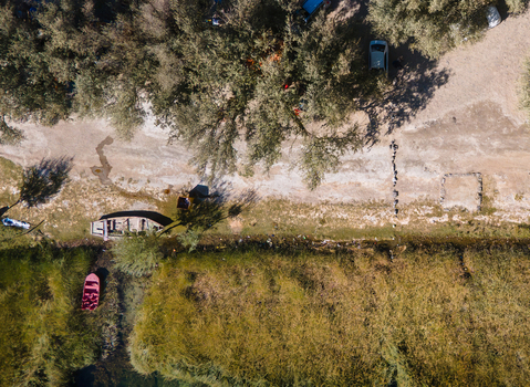 Aerial view of Blind Lake Sarfaranga Shigar with a small boat and a red boat moored along the sandy shore surrounded by trees and lush vegetation in Skardu Gilgit Pakistan.