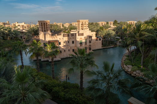 View of traditional Arabic architecture with wind towers and lush palm trees along a canal at the Madinat Jumeirah Dubai Dubai United Arab Emirates. View of traditional Arabic architecture with wind towers and lush palm trees along a canal at the Madinat Jumeirah Dubai Dubai United Arab Emirates.