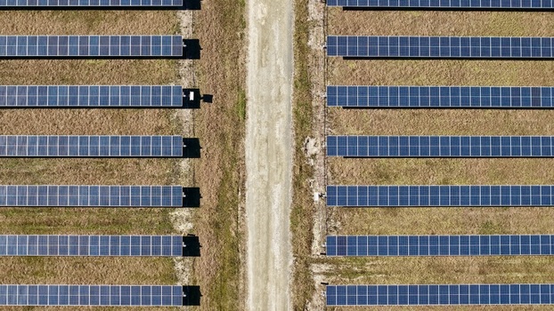 Aerial view of neatly arranged solar panels casting shadows on the arid land alongside a sandy path Elkton Florida United States. Aerial view of neatly arranged solar panels casting shadows on the arid land alongside a sandy path Elkton Florida United States.