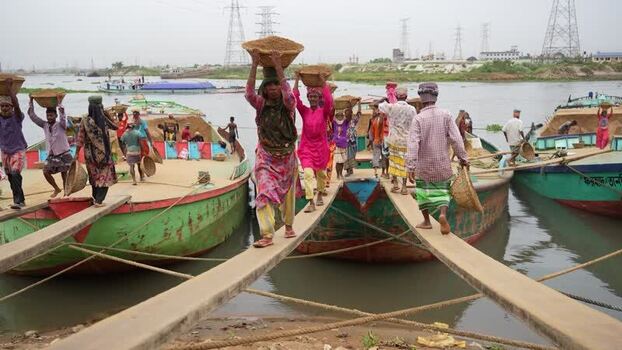 View of workers carrying sand from boats in Aminbazar Bangladesh.