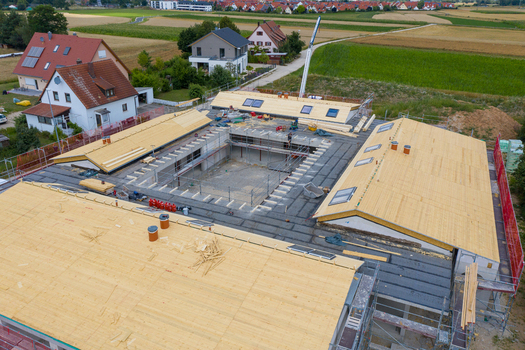 Igensdorf Germany 11 May 2024 Aerial view of a large building under construction with timber roof framing and scaffolding in a residential area. Igensdorf Germany 11 May 2024 Aerial view of a large building under construction with timber roof framing and scaffolding in a residential area.