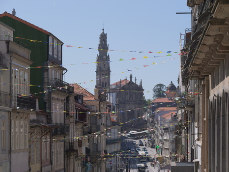 View of the historic Clerigos Church and its iconic tower rising above narrow streets in Porto adorned with colorful festive bunting between traditional buildings Porto Porto District Portugal. View of the historic Clerigos Church and its iconic tower rising above narrow streets in Porto adorned with colorful festive bunting between traditional buildings Porto Porto District Portugal.