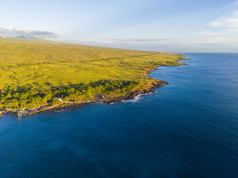 Aerial view of Mahukona Beach Park with its rocky coastline lush green hills and deep blue ocean waters under a clear sky Waimea Hawaii United States.