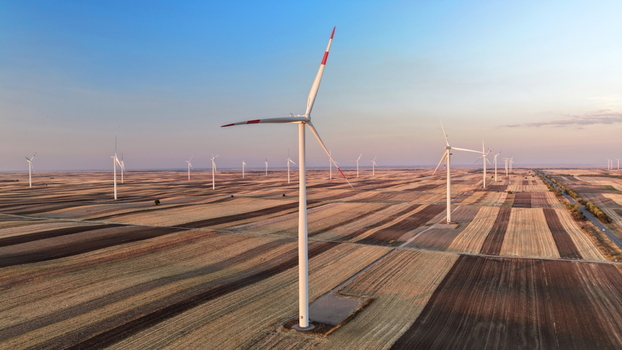 Aerial view of wind turbines standing in vast agricultural fields under a clear sky in Vladimirovac Vojvodina Serbia.