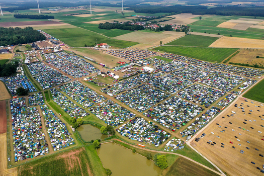 Herzogenaurach Germany 26 July 2025 Aerial view of the Open Beatz Festival campsite with thousands of colorful tents and parked cars spread across green fields and farmland.
