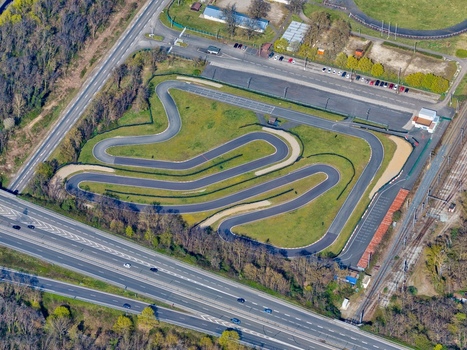 Aerial view of a go kart track nestled amid lush greenery a vibrant contrast against the gray asphalt of the surrounding roads Sausheim Grand Est France.