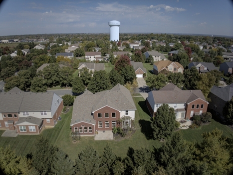 Aerial view of a suburban neighborhood with residential houses lush green trees and a prominent water tower in the background in Mason Ohio United States.